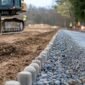 lugar de construccion con maquinaria que prepara una superficie de carretera con grava y tierra 85x85